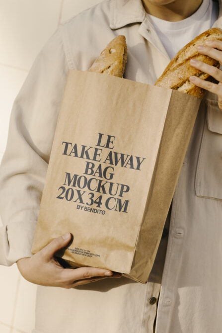Person holding brown paper bag mockup with bread inside, ideal for packaging design. Keywords: packaging mockup, takeaway bag, design resource.