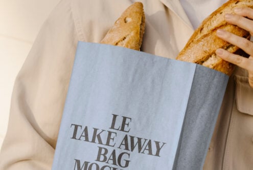 Mockup of a person holding a blue bag with baguettes inside featuring typography design. Perfect for designers seeking creative packaging templates.