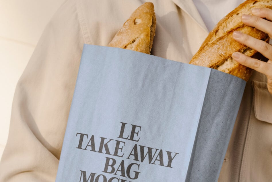 Mockup of a person holding a blue bag with baguettes inside featuring typography design. Perfect for designers seeking creative packaging templates.
