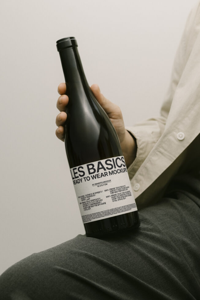 Designer holding a wine bottle with modern label mockup. Ideal for showcasing branding concepts for packaging design projects. Mockup, template, design asset.