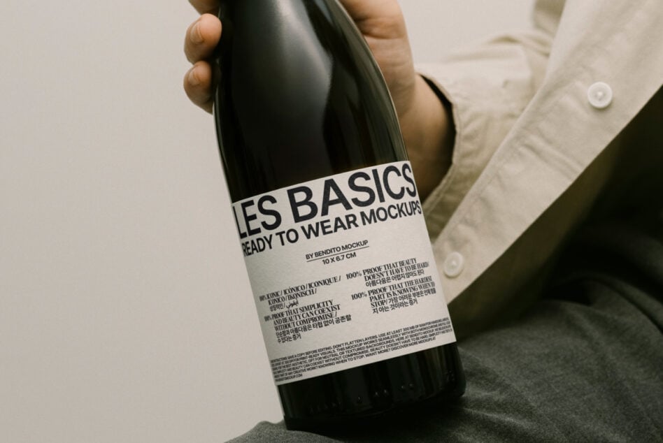 Wine bottle with white label held at angle, seated figure in neutral clothing