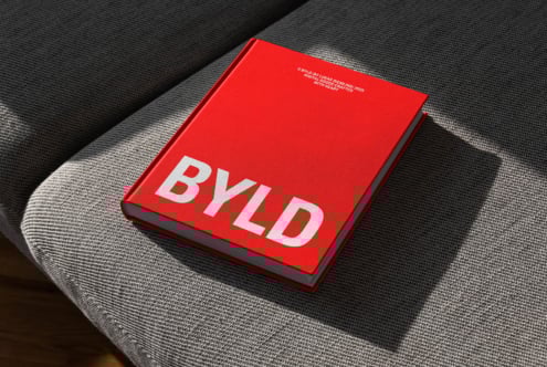 Red hardcover book mockup on a textured grey fabric surface for design presentations branding marketing realistic shadows minimalist style typography