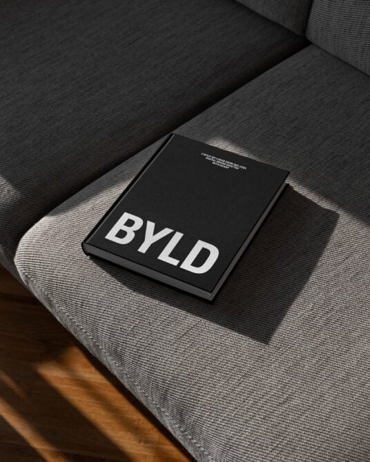 Black hardcover book on fabric surface with white 'BYLD' text on front cover