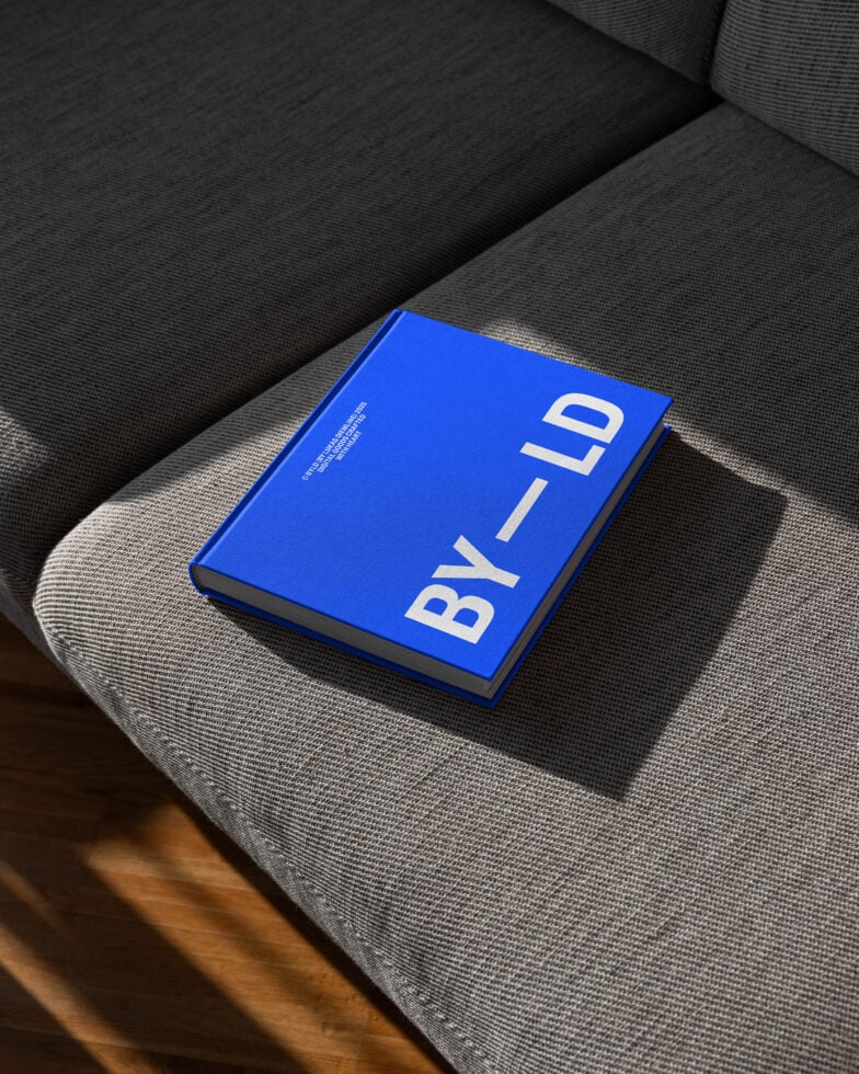 Blue hardcover book mockup on gray fabric couch, optimal for design presentations. Ideal resource for designers seeking realistic product visuals.