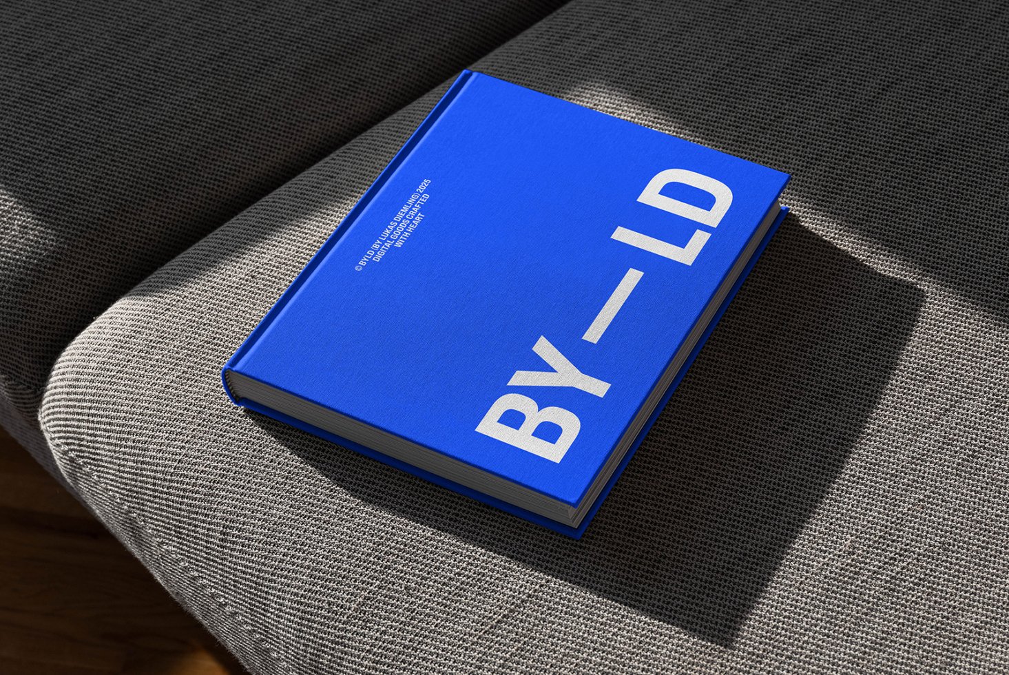 Blue hardcover book on grey fabric surface sunlight angled Mockup asset for graphic designers sleek minimal modern text typography professional layout