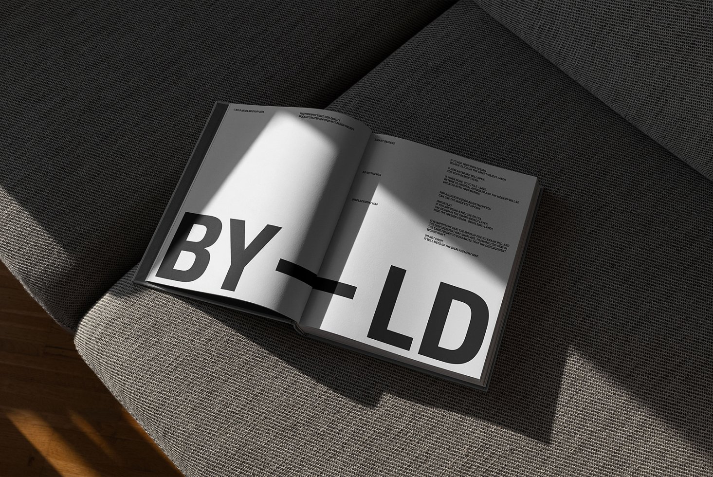 Open typography book on a textured gray couch with sunlight casting shadows across the pages. Keywords: mockup, typography, design asset, book layout.