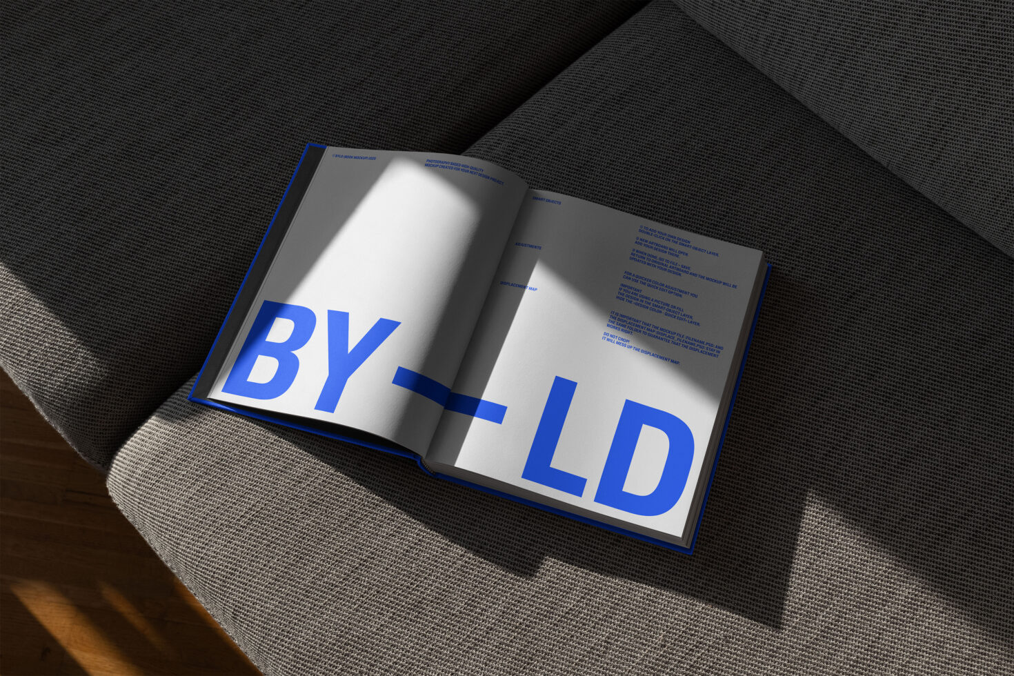 Open book on a gray sofa with bold blue text and minimalist design ideal for mockup templates and graphic design inspiration for designers.