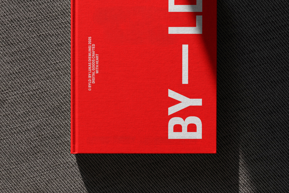 Red hardcover book with large silver BY1 letters on spine against gray fabric