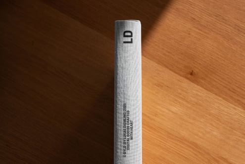 Tall gray fabric book spine with minimalist logo on wood background
