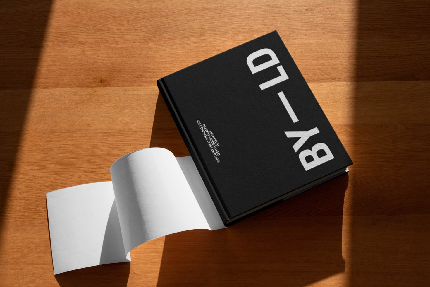 Hardcover book mockup on wooden surface. Empty pages open in sunlight. Ideal for showcasing graphic templates and design projects for designers.