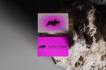 Two modern business card mockups showcasing bold fonts and vibrant pink and gray designs on a textured rock surface ideal for designers.