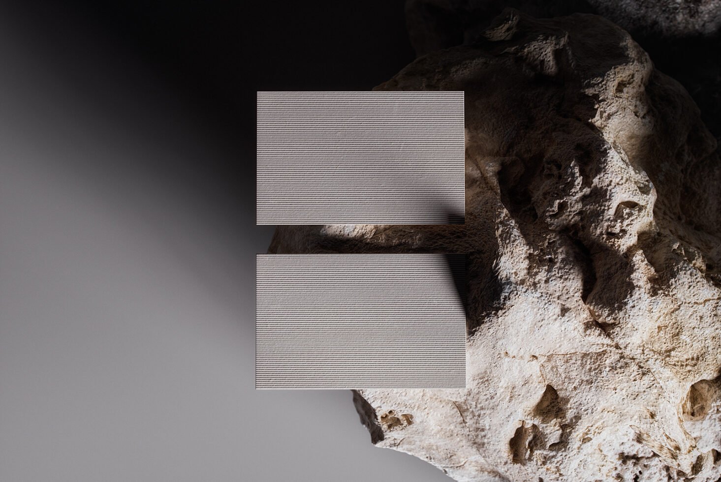 Business card mockup on textured rock background with natural lighting shadows. Ideal for showcasing card designs. Perfect for designers marketing.