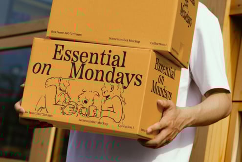 Person holding boxes with Essential on Mondays text and illustrations mockup design perfect for packaging templates and designer resources.