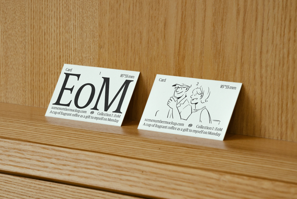Cream colored business cards with EoM typography on natural wood surface