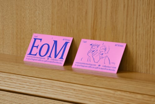 Pink business card mockup on wooden surface featuring bold typography with a modern design. Ideal for creative projects and branding presentations.