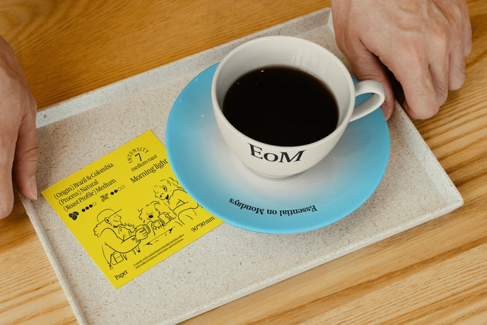 Coffee cup on blue saucer with design print on wooden tray holding a yellow coffee info card ideal for graphic template and mockup use for designers.