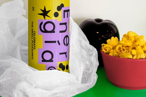 Colorful energy drink can with bold typography next to popcorn bowl and decor object. Suitable for mockup, graphic design projects, branding assets.