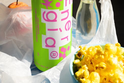 Colorful snack scene with vibrant drink can label design next to popcorn bowl and bottle, perfect for graphic design and branding inspiration.