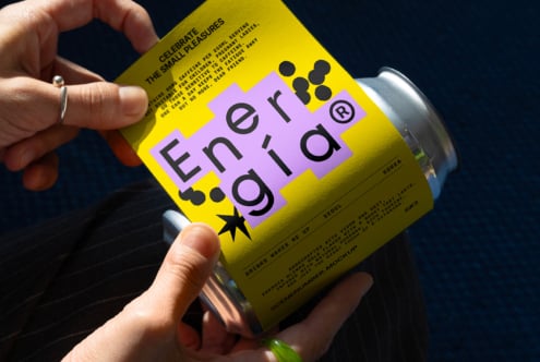 Person holding a vibrant yellow can mockup with purple and black typography design. Ideal for graphic designers seeking creative packaging inspiration.