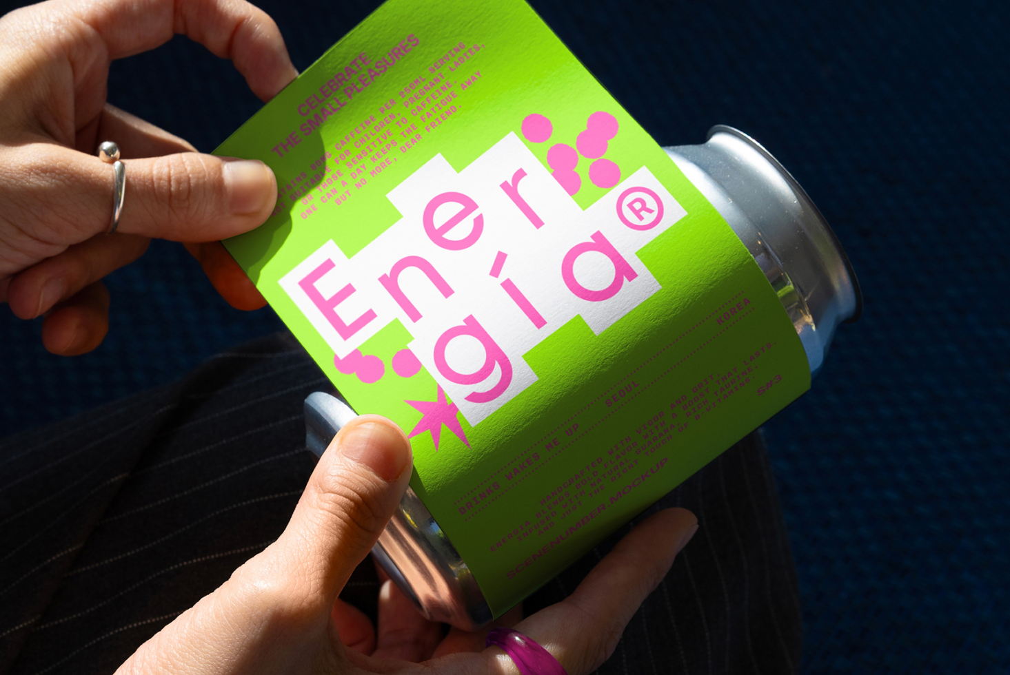 Close-up of a vibrant green energy drink label mockup in hands, featuring bold pink typography. Perfect for product packaging design and branding projects.