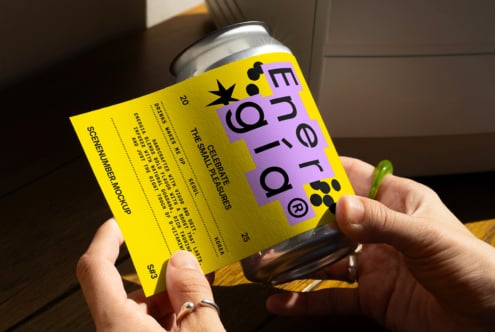 Hand holding a can with vibrant yellow and purple label design in sunlight mockup. Ideal for packaging designers, showcasing branding creativity.
