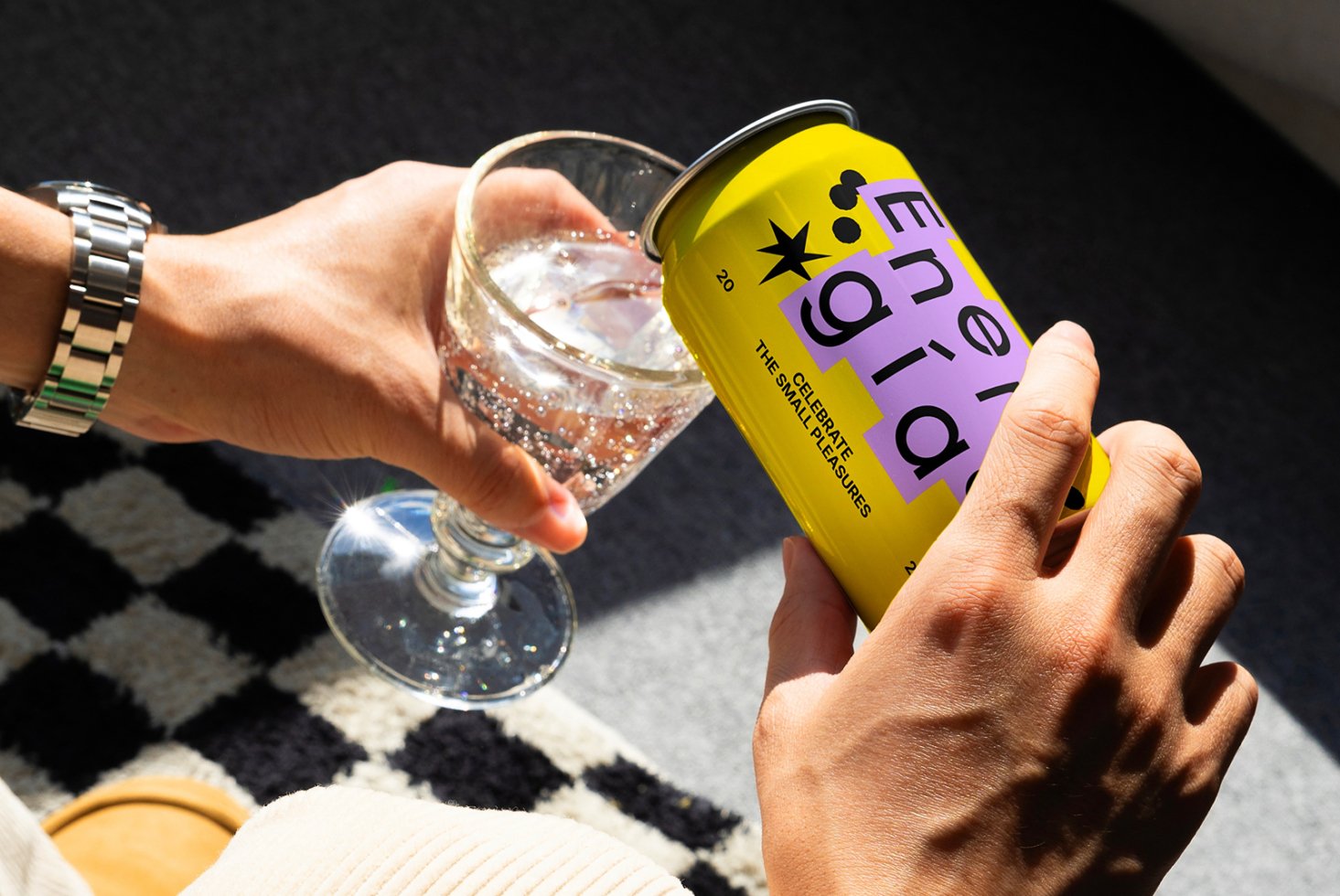 Hands pouring drink from colorful can into glass. Creative beverage packaging mockup. Modern design, yellow can with unique typography. Graphic asset.
