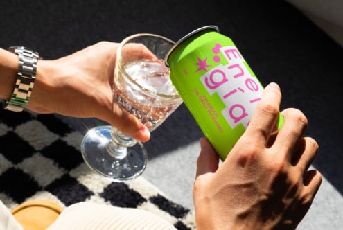 A person pours a drink from a vibrant green can into a sparkling glass in sunlight branding typography design mockup perfect for graphic design projects.