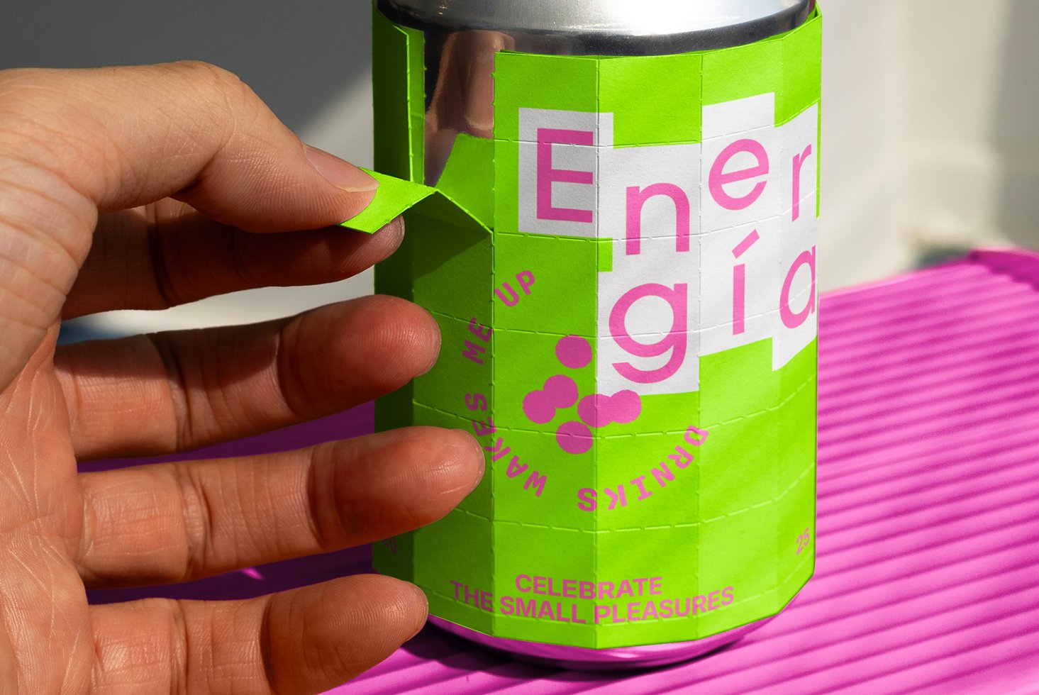 Hand peeling a vibrant lime green and pink can label, showcasing modern typography. Ideal for designers seeking beverage packaging mockup inspiration.