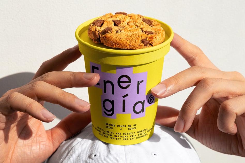 Hand holding bright yellow coffee cup with cookie on top. Modern typographic design template, vibrant colors. Ideal for packaging mockup, designer assets.
