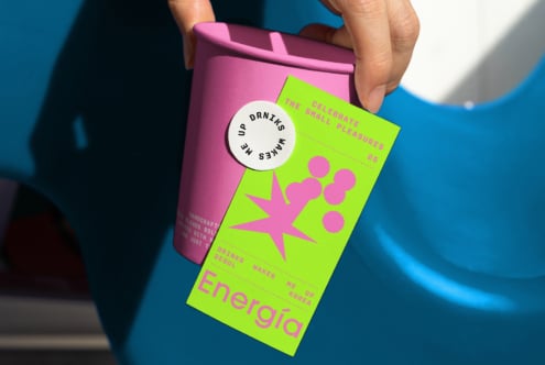 Hand holding vibrant pink cup with neon green label. Abstract design for templates packaging mockups. Ideal for graphic designers commercial use.