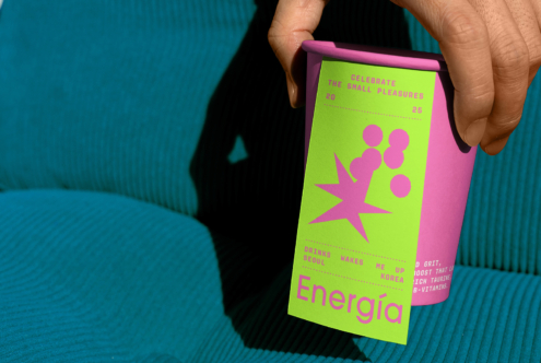 Hand holding a purple cup with a bright green sleeve featuring abstract design and text. Perfect for branding mockup, packaging template, graphic design.