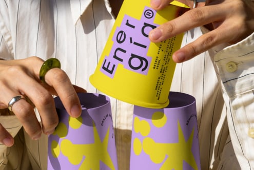 Colorful packaging mockup featuring hands holding purple and yellow cylindrical containers with bold typography ideal for designers seeking unique graphics.