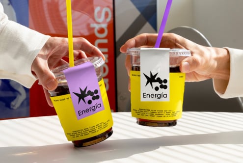 Two hands holding iced coffee cups with yellow and purple branded sleeves labeled Energia. Ideal for mockup designs and packaging templates.