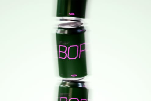 Minimalistic mockup of green beverage cans with bold pink typography design, suitable for creative packaging projects and branding presentations.