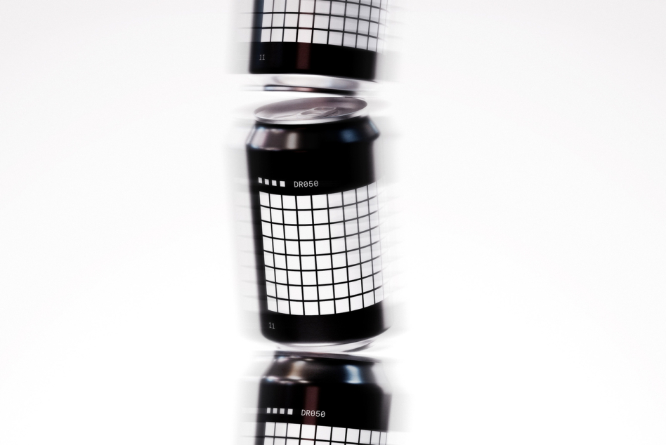 Black cans stacked with grid pattern wrap, DR850 label, chrome lids, motion effect