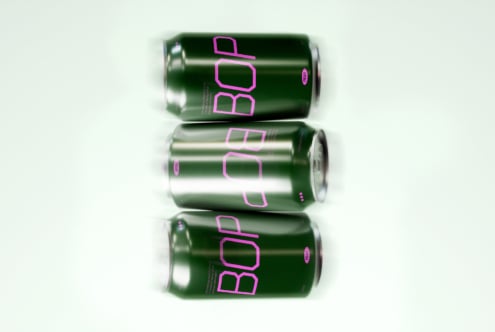 Mockup of three soda cans design. Green aluminum cans with bold pink typography arranged neatly for digital asset preview. Ideal for designers.