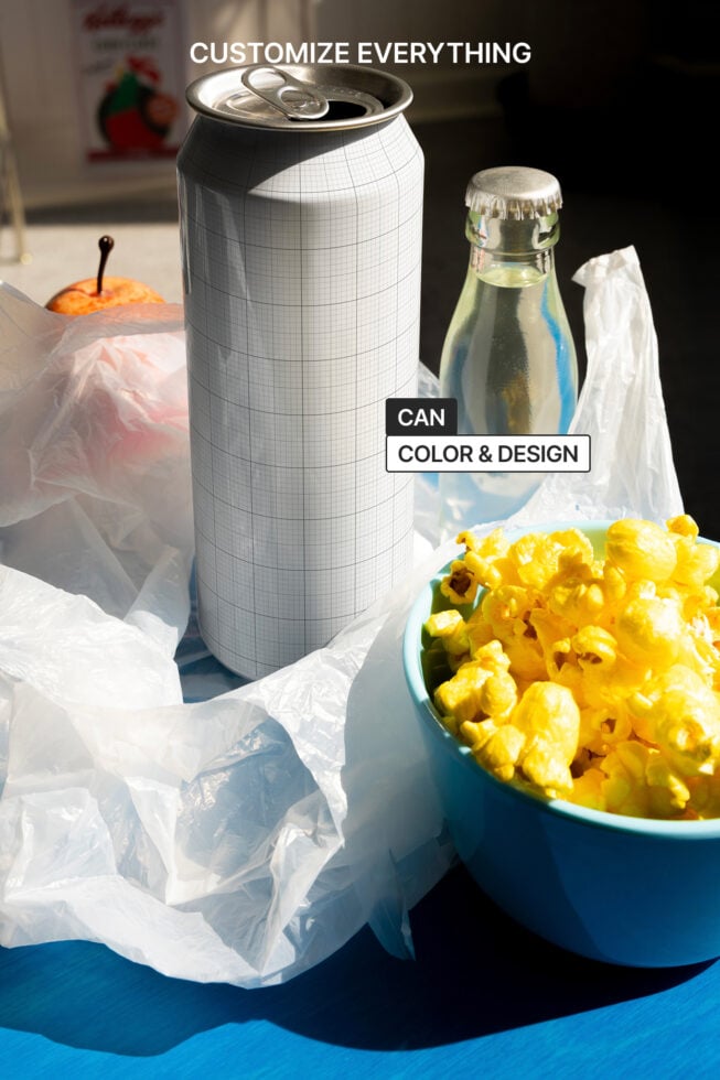 Drink can mockup on table with soda bottle and popcorn highlighting custom design. Ideal for product packaging design showcasing customization options.