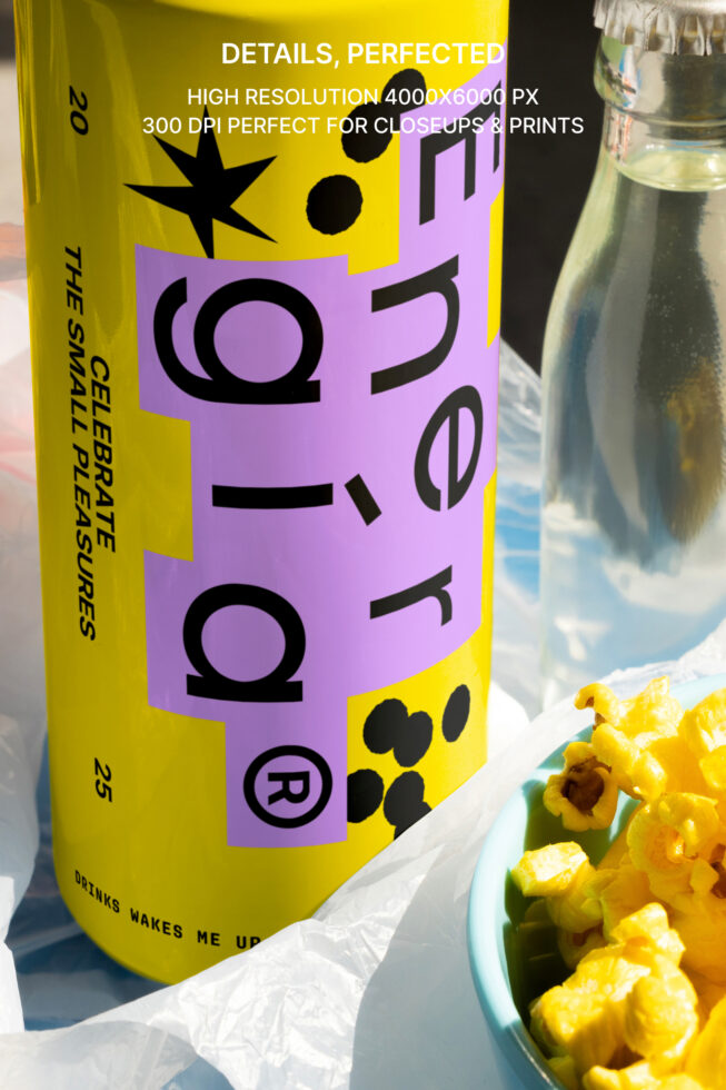 Yellow energy drink can with bold purple label, next to a teal bowl of popcorn. Text details image resolution. Perfect for packaging mockup designers.