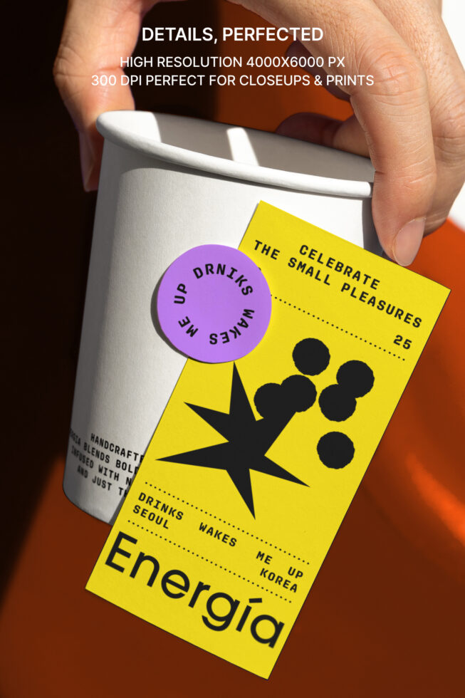 Hand holding a paper cup with a vibrant yellow and purple label design featuring bold text and graphics. Perfect for packaging mockups and graphic designers.