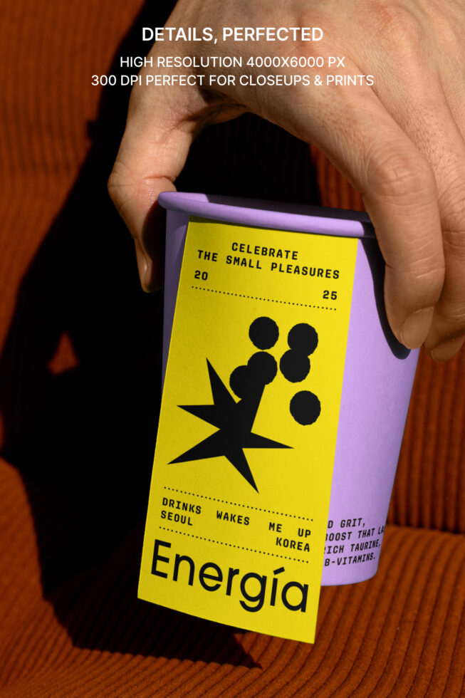Hand holding a purple cup with bold yellow graphic label; modern design mockup template for branding, prints, and packaging in high resolution.