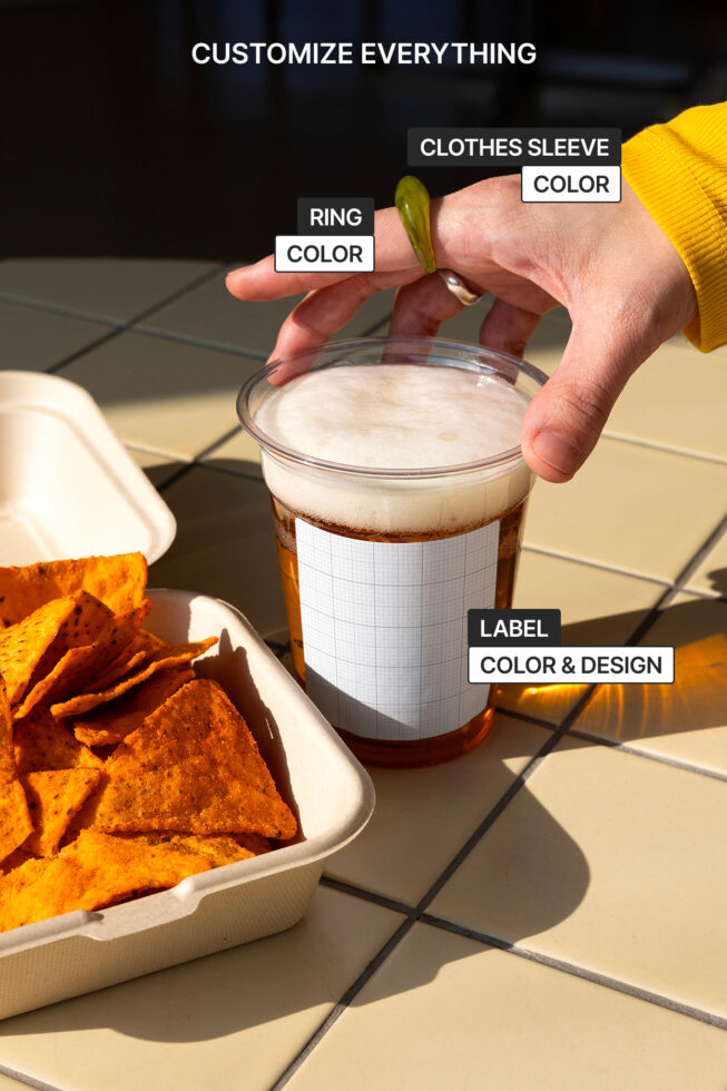 Customizable mockup of a hand holding a drink cup beside a tray of chips. Change ring color, sleeve color, and label design for branding.
