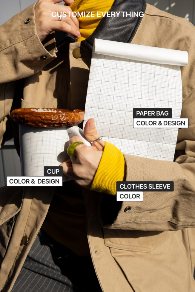 Person holding a customizable paper bag and cup with grid design. Yellow sleeve visible. Keywords for Designers: Mockup, Template, Graphics, Customizable