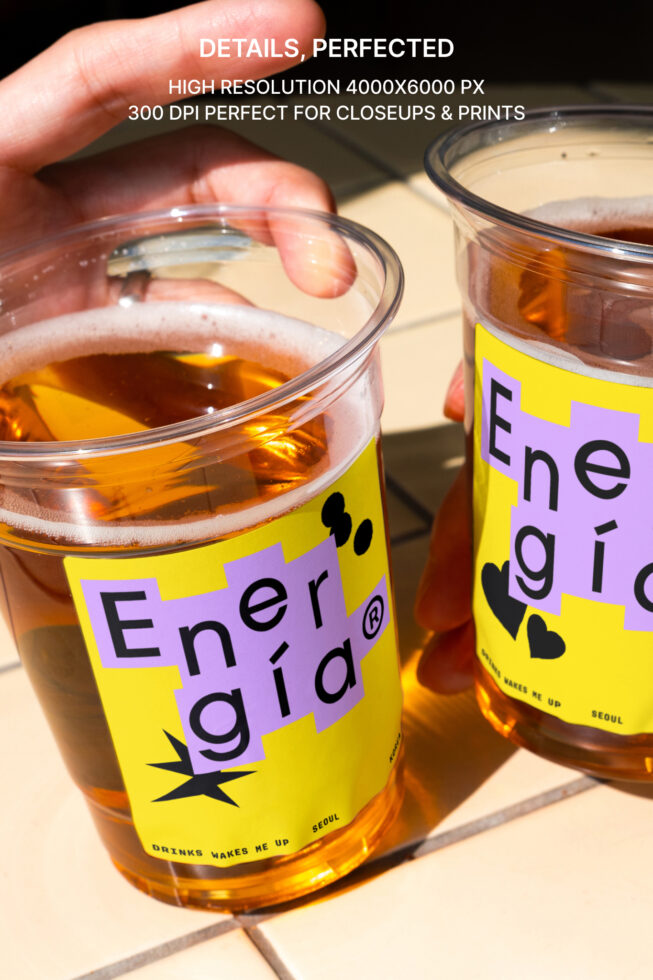 Close-up of two transparent cups with tea featuring vibrant yellow and purple graphic labels. High-resolution, ideal for mockup designs and branding.