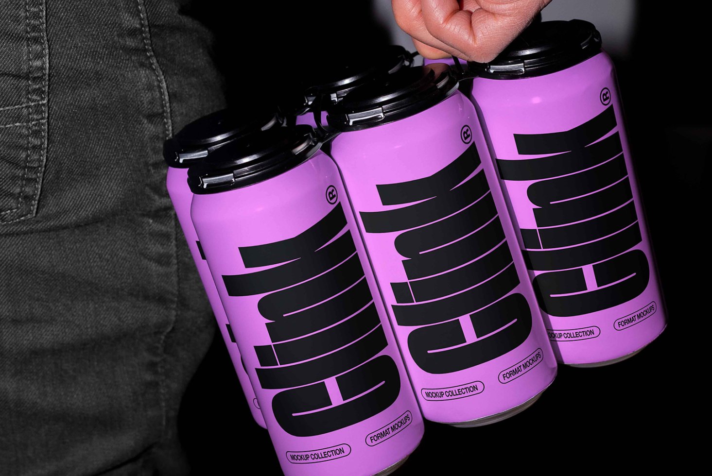 Hand holding a set of four purple beverage cans showing bold black typography design. Perfect for packaging mockups, graphic resources, and templates.