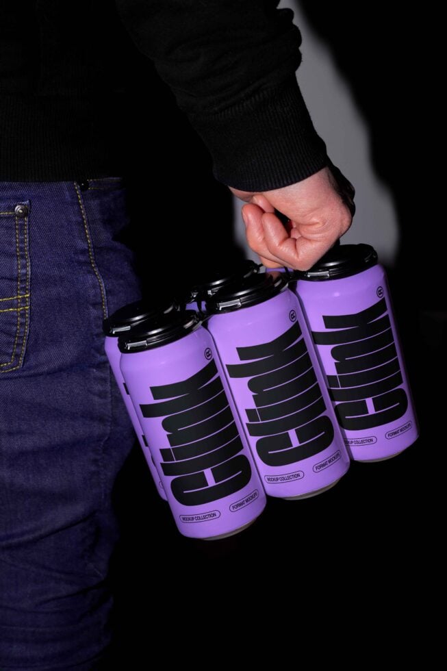 Hand holding four purple cans with bold black typography. Ideal for product mockups packaging design branding graphic templates creative assets.
