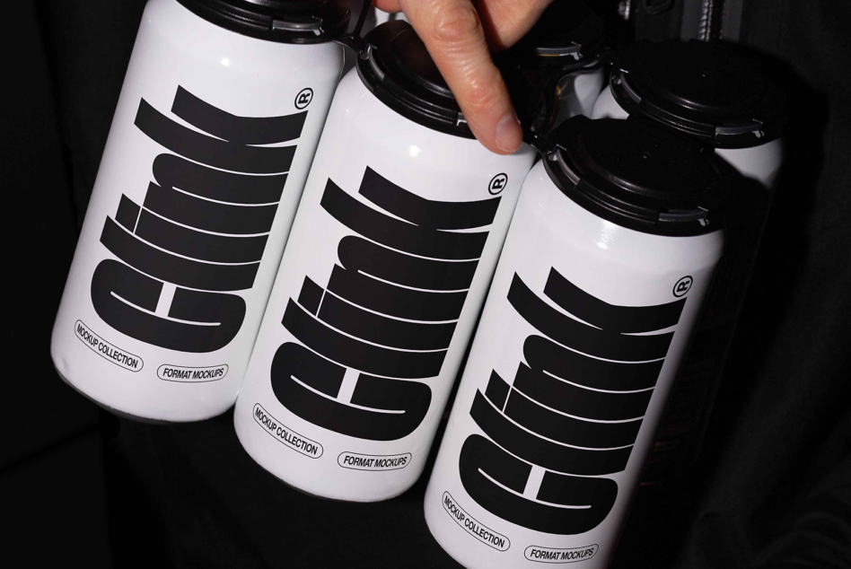 Three white aluminum cans with black horizontal stripe layout in hand