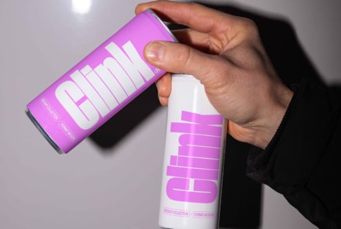 Two hands holding clinking beverage cans with modern labels. Minimalist design. Perfect for mockup projects. Ideal for designers creating packaging.