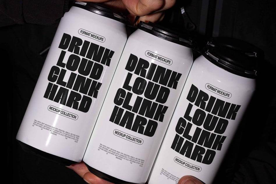 Three white cans with thick black sans serif text held by hands on dark background
