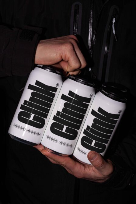 Three white cans with bold black striped typography held together in hands