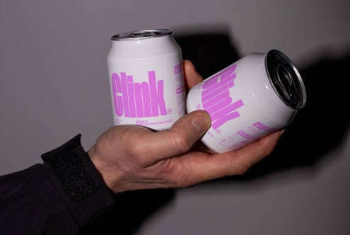 Hand holding two white and pink soda cans labeled Clink, perfect for branding mockup design, packaging templates, and beverage graphics.